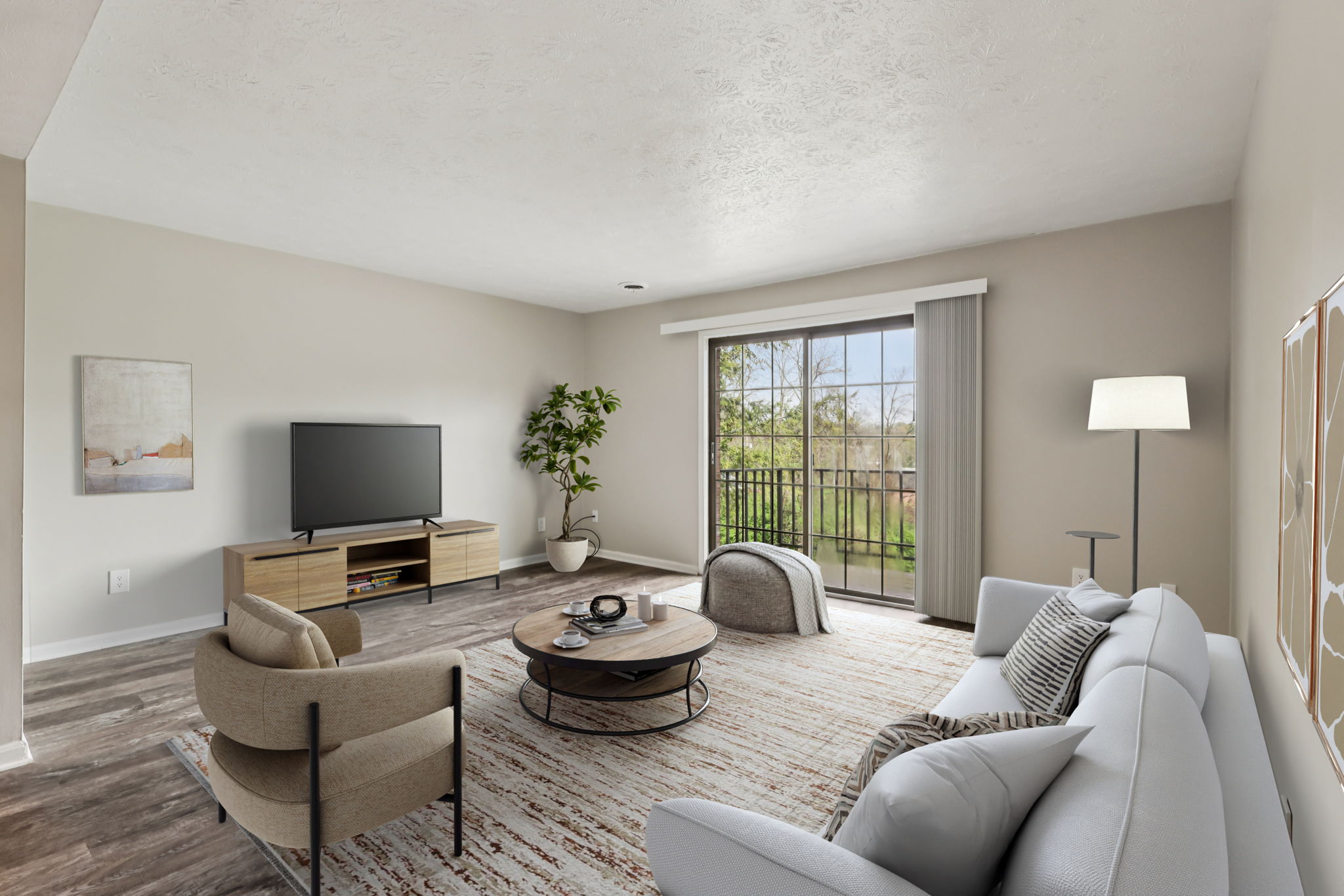 A living room with a grey couch, a chair, a coffee table, a television, and a potted plant.